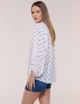 Blusa holgada de gasa texturizada color blanco con estampado de lunares negros, escote en V con botones frontales, mangas 3/4 abullonadas y puños elásticos.