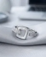 Anillo de acero con diseño de hebilla cuadrada que incluye incrustaciones de nácar y circonias en la banda.