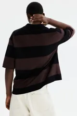 Remera polo de punto con diseño a rayas horizontales en color negro y marrón, de manga corta, cuello camisero con abertura en V y corte holgado.