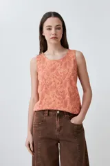 Musculosa de calce holgado en color durazno, con estampado paisley en relieve (puff print) en tonos rojizos. Presenta cuello redondo y diseño sin mangas.