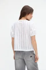 Blusa negra de broderie con mangas cortas abullonadas, cuello redondo y calce clásico.