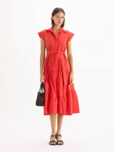 Vestido camisero largo color rojo, de mangas cortas con hombros estructurados y falda escalonada con volados. Presenta cierre frontal con botones y lazo ajustable en la cintura del mismo material.