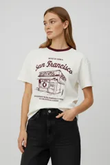 Remera de algodón de corte holgado con cuello redondo y mangas cortas. Presenta un estampado gráfico frontal en color bordó con la inscripción 'San Francisco' y el dibujo de un local comercial.