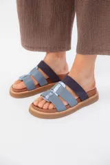 Sandalias bajas de cuero color celeste con tiras anchas y detalle de tira plateada en el centro.