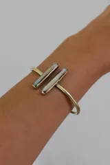 Pulsera dorada rígida con apliques de nácar.
