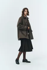 Chaqueta de gamuza sintética color verde militar, con cuello camisero y cierre frontal de botones. Presenta un diseño de corte amplio con bolsillos delanteros de solapa y mangas largas. El material tipo suede ofrece una textura suave y un estilo clásico de inspiración masculina.