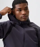 Campera deportiva Get Over de poliéster tecnológico, de color gris oscuro con bandas negras decorativas en los hombros y mangas. Cuenta con capucha ajustable, cierre frontal con cremallera, y puños y cintura elastizados.