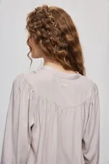Blusa celeste de manga 3/4 con cuello mao, botonadura frontal y detalles calados en V con frunces. Presenta mangas con volumen y silueta fluida.