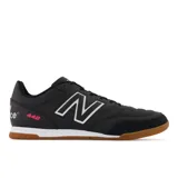 Championes de fútbol New Balance modelo 442 V2 Team, color negro con detalles en blanco y rosa. Presentan un empeine de cuero con costuras reforzadas, puntera de gamuza y suela de goma color caramelo diseñada para césped artificial o asfalto.