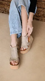 Sandalias de plataforma corrida color beige, con capellada de cuero y tira ajustable con hebilla en el tobillo.