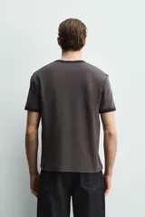 Camiseta de corte regular fit, color gris oscuro, con cuello redondo y bordes de mangas en color azul marino a contraste.