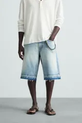 Bermuda de denim de algodón, color negro lavado, de corte ancho (baggy fit) y tiro medio. Presenta cinco bolsillos y bajo con acabado irregular deshilachado.