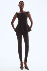 Top largo de punto tupido, color negro, con hombros descubiertos, corte ajustado y diseño acampanado estilo peplum desde la cintura.