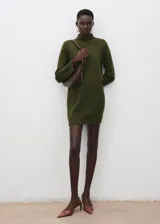 Vestido corto de punto en color verde oliva, con cuello alto y detalle de botones metálicos en el hombro. Presenta mangas largas y un corte recto y ajustado.