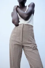 Pantalón de tiro alto con estampado de cuadros vichy en tonos marrón y blanco, con bolsillos laterales de vivo y corte recto.