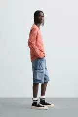 Bermuda de denim de algodón, color celeste lavado, de corte relajado (relaxed fit). Presenta cinco bolsillos, incluyendo bolsillos cargo plastrón con solapa en las perneras.