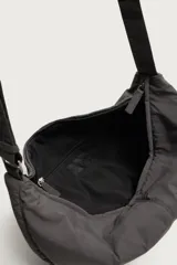 Bolso de hombro tipo hobo de nylon negro, con diseño curvo y asa ajustable. Cuenta con compartimento principal con cierre de cremallera y bolsillo interior con cremallera.