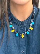 Collar corto con diseño multicolor compuesto por cuentas de cristal checo, piedras naturales y piezas de acrílico en tonos azul, celeste y amarillo, con cierre de cadena de acero quirúrgico.