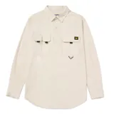 Camisa de manga larga color beige, estilo utilitario, con cuello clásico y cierre frontal de botones. Presenta tres bolsillos de carga en el pecho con solapas y cierre de velcro, además de un detalle de argolla triangular metálica y etiqueta con logo de la marca.