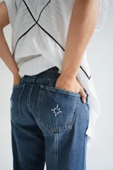 Pantalón de jean gris oscuro de corte recto, tiro medio y largo. Diseño con costuras verticales y lavado con sobreteñido.