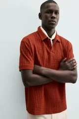 Polo de hombre color terracota con cuello solapa y cierre frontal de botonadura. Presenta un tejido texturizado tipo seersucker y un calce relajado.