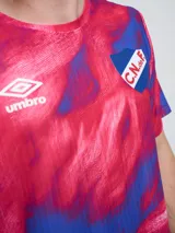Remera de entrenamiento Umbro del Club Nacional de Football, modelo Press, para hombre. Diseño en tonos de rojo con patrón estampado tipo humo o abstracto, cuello redondo y mangas cortas. Incluye el logo de Umbro y el escudo del club en el pecho.