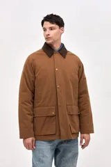 Campera de gabardina color marrón con cuello de pana en tono oscuro. Presenta cierre frontal con botones a presión, bolsillos laterales con solapa y diseño de calce clásico.