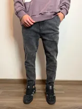 Jean de corte mom al tobillo en color gris con efecto lavado, de tiro medio y ajuste holgado en las piernas.