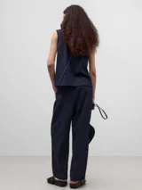 Pantalón de vestir azul marino, de corte recto, con bolsillos laterales y traseros. Se ajusta a la cintura con cinturón de cuero marrón.