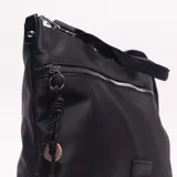 Bolso bandolera negro de material sintético, con forma rectangular y textura lisa. Posee un bolsillo frontal con cierre metálico plateado y un parche rectangular de cuero sintético en la parte inferior central. Incluye asas cortas de tela y una correa larga ajustable y desmontable.