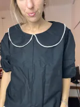 Blusa negra de lino con cuello Peter Pan blanco y mangas cortas abullonadas.
