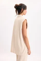 Chaleco sastrero largo de lino color beige melange, sin mangas, con cuello solapa y cierre frontal de un botón.