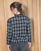 Camisa de algodón con estampado de rayas verticales finas, cuello alto con volados, cierre frontal con botones dobles y mangas largas con puños elásticos terminados en volados.