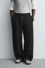 Pantalón jogger de corte relajado y pernera ancha, confeccionado en tejido de algodón con interior perchado. Presenta cintura elástica con cordón interior, bolsillos laterales y un bolsillo trasero de plastrón.
