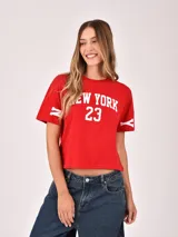 Remera crop top color rojo con estampado blanco de "NEW YORK 23" en el frente y rayas blancas en las mangas.