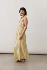 Vestido largo color amarillo con tirantes finos cruzados en la espalda, escote en V y diseño fluido con falda amplia.
