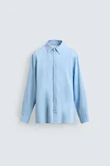 Camisa de corte relajado confeccionada en tejido fluido con mezcla de viscosa, color celeste. Presenta cuello solapa, manga larga con puños abotonados y cierre frontal de botones.