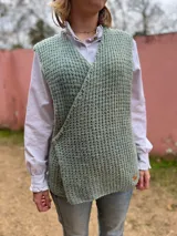 Chaleco tejido en punto inglés de lana merino pura, color verde menta, con diseño cruzado al frente y cierre lateral con botón.