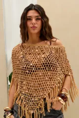 Top corto tejido en crochet de color beige con diseño de red, adornado con lentejuelas circulares y flecos en el borde inferior.