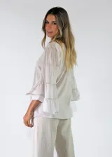 Blusa de algodón color gris oscuro con efecto gastado, mangas largas amplias con múltiples volados escalonados y terminaciones deshilachadas.