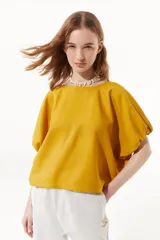 Top corto amarillo de calce oversize con cuello redondo y mangas abullonadas.