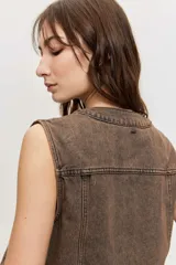 Chaleco de denim marrón con efecto acid wash y apliques de strass distribuidos por toda la prenda, sin mangas y con cierre frontal de botones.