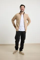 Cardigan de tejido de punto color verde militar, con cierre frontal de metal y cuello redondo. Presenta detalle de tejido plano en la cartera del cierre y en los bolsillos laterales.