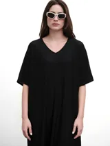 Vestido midi negro con cuello en V, mangas cortas y aberturas laterales. Confeccionado en tejido fluido con un toque de lurex.