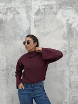 Polera de punto color bordó, con cuello alto abierto lateralmente, mangas largas amplias y corte recto.