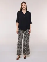 Blusa verde de calce holgado y caída fluida, confeccionada en tejido tipo crepé. Cuenta con cuello camisero con solapa, escote en V y cierre parcial al frente con tres botones metálicos. Las mangas son largas con puños abotonados.