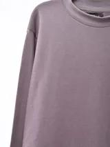 Buzo de cuello redondo, manga larga, con puños y ruedo acanalados, confeccionado en tejido liso de color gris oscuro.