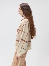 Sweater de punto grueso con cuello redondo, diseño de calce holgado y mangas amplias. Presenta un estampado geométrico de cuadros en tonos azulados con un gráfico central en color naranja y detalles bordados.