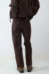 Pantalón de tiro medio con acabado efecto ante, diseño de pierna recta, con bolsillos laterales y traseros, y cierre frontal con cremallera metálica.