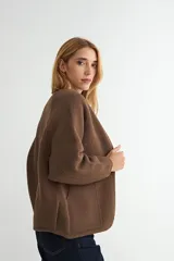 Campera corta de paño color negro, con cuello redondo, mangas largas y cierre frontal con botones a presión metálicos.